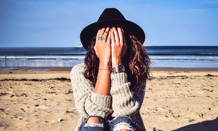 woman at beach with head in hands